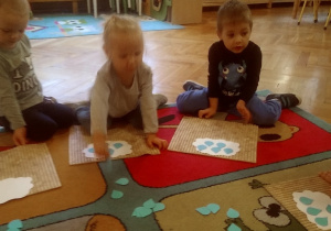 dzieci na dywanie układają kropelki wycięte z papieru kolorowego
