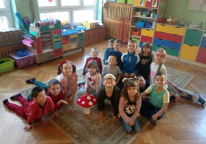 Dzieci z grupy V siedzą na dywanie i pozdrawiają rodziców.