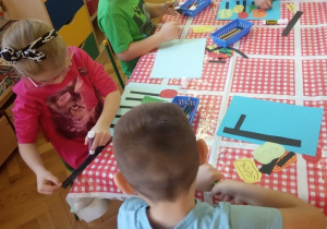Dzieci z grupy V wykonują prace plastyczne o drzewach w parku jesienią.
