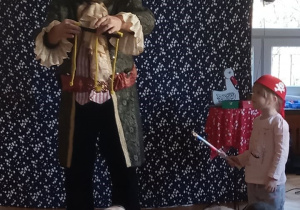 Iluzjonista prezentuje magiczne sztuczki, które oglądają dzieci.