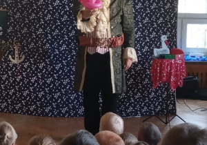 Iluzjonista prezentuje magiczne sztuczki z króliczkiem, które oglądają dzieci.