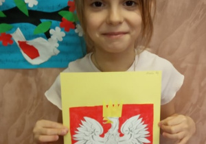 Dziewczynka prezentuje swą pracę "Godło Polski".