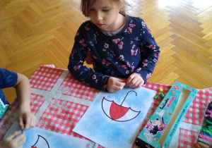 Dziecko wykleja plasteliną kontur parasolki