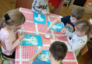 Dzieci wykonują prace plastyczne.