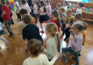 Dzieci patrzą na pana prowadzącego zabawy i naśladują jego ruchy.