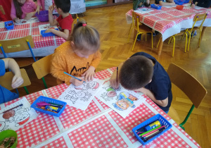 Dzieci wykonują karty pracy przy stoliku