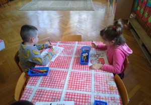 Dzieci wykonują karty pracy przy stoliku