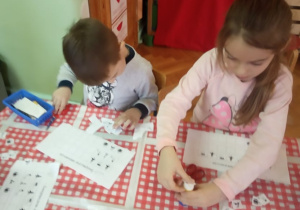 Dzieci wycinają brakujące obrazki potrzebne do dopełnienia sekwencji.