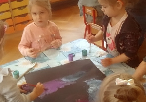 dzieci malują czarny karton farbami