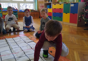 Dziecko układa kartkę na macie do kodowania