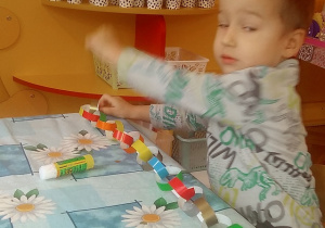 dzieci sklejają paski z kolorowego papieru