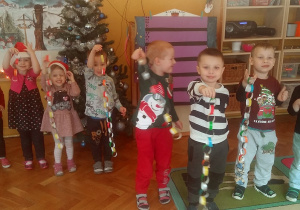 dzieci prezentują swoje łańcuchy na choinkę z kolorowego papieru