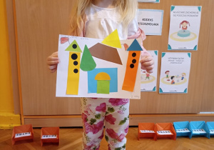 dziewczynka prezentuje prace plastyczną - zamek z figur geometrycznych