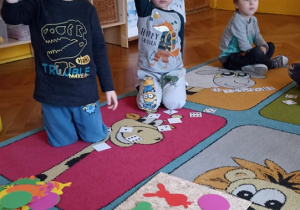 dzieci siedzą na dywanie. na dywwanie leżą karteczki z cyframi