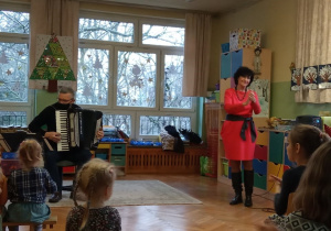 Dzieci słuchają utworów granych przez muzyka na akordeonie.