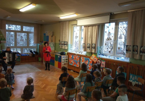 Dzieci słuchają utworów granych przez muzyka na akordeonie.