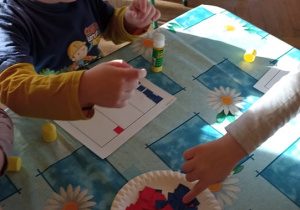 dzieci wyklejają flagę Francji papierwm kolorowym