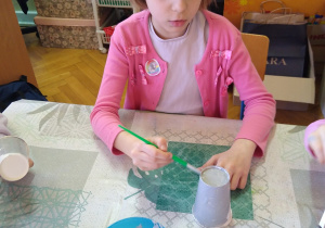 Dziewczynka maluje papierowy kubek na szaro
