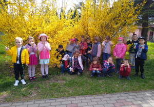 Dzieci pozują przy krzewie forsycji
