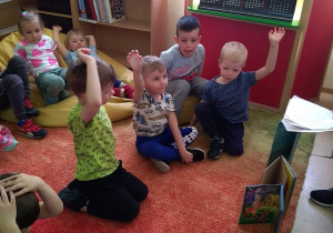 Dzieci siedzą na dywanie w czytelni