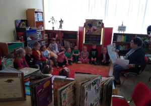 Dzieci słuchają czytanej przez panią bibliotekarkę książki