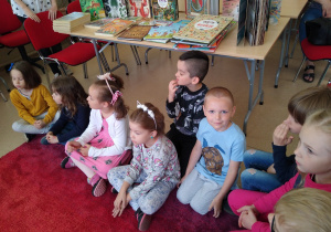 Dzieci słuchają czytanej przez panią bibliotekarkę książki
