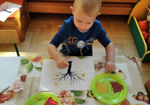 Chłopiec wykonuje pracę plastyczną.