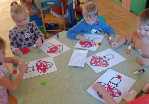 dzieci wyklejają papierem kolorowym muchomora