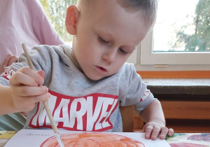 Chłopiec wykonuje pracę plastyczną