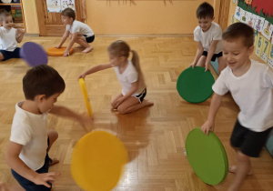dzieci ćwiczą z kolorowymi krążkami