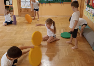dzieci ćwiczą z kolorowymi krążkami