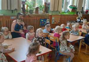 Dzieci siedzą przy stolikach, słuchają wypowiedzi pracowników Straży Miejskiej