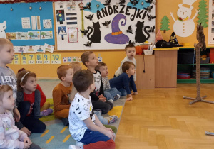 dzieci siedzą na dywanie i patrzą na sowy