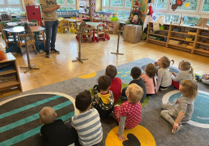 Dzieci siedzą na dywanie i słuchają ciekawostek o sowach
