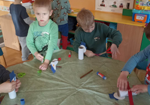 dzieci oklejają papierem kolorowym rolkę