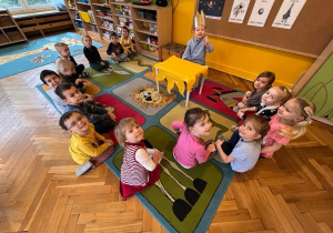 Dzieci siedzą w kole i pozują do zdjęcia
