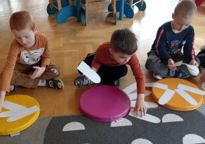 dzieci układają białe płatki kwiatka do kolorowego krążka