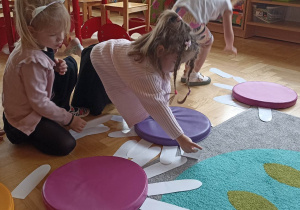 dzieci układają białe płatki kwiatka do kolorowego krążka