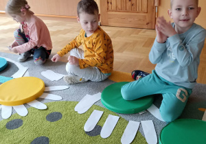 dzieci układają białe płatki kwiatka do kolorowego krążka