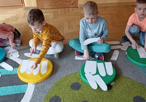 dzieci układają białe płatki kwiatka do kolorowego krążka