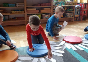 dzieci układają białe płatki kwiatka do kolorowego krążka