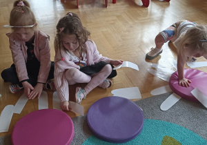 dzieci układają białe płatki kwiatka do kolorowego krążka