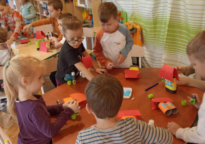 dzieci wyklejają domki z rolek i papieru kolorowego