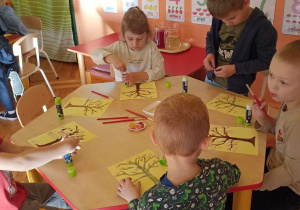 dzieci wyklejają jesienne drzewa