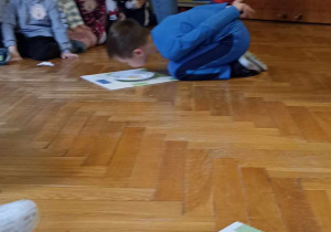 chłopiec klęczy przed talerzykiem
