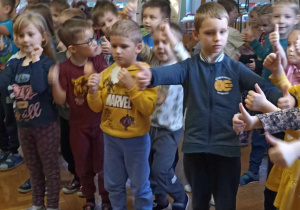 dzieci stoją i wyciągają ręce przed sziebie