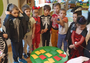 dzieci stoją przy stoliku na którym leżą kolorowe karteczki