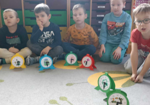 dzieci siedzą i ustawiają godzinę na swoich zegarkach
