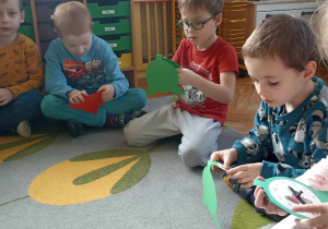 dzieci siedzą i ustawiają godzinę na swoich zegarkach