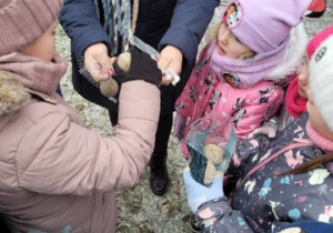 Dzieci wkładają jedzenie do karmników.
